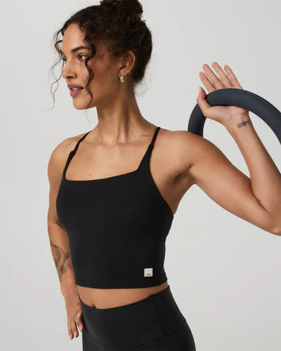 Woman in a Vuori - AllTheFeels Strappy Back top holding a yoga wheel against a plain background