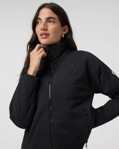 Woman wearing a black Vuori - Canyon Insulated Jacket against a white background