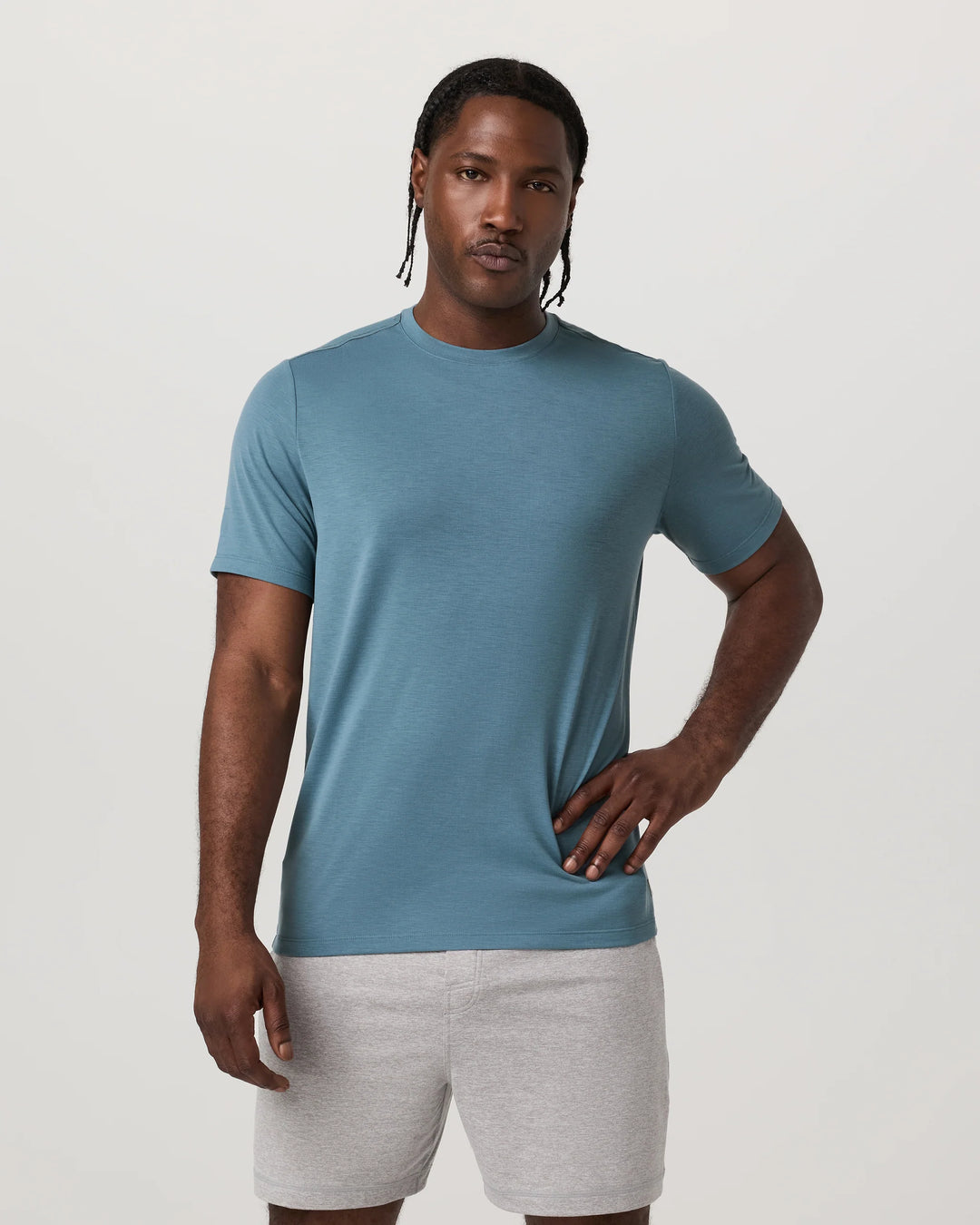 Man wearing a Vuori_-_Current_Tech_Tee in Pond and gray shorts on a white background