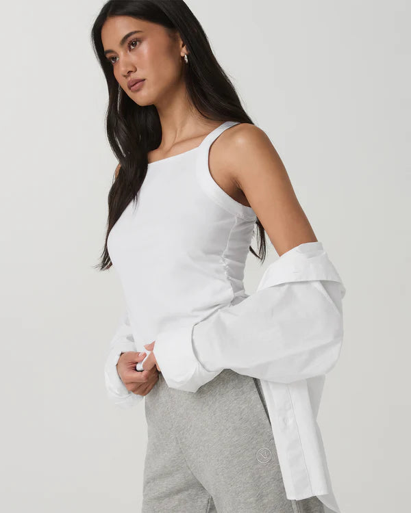 Woman wearing a Vuori - Energy Racerback Tank with ruched details and gray pants on a plain background