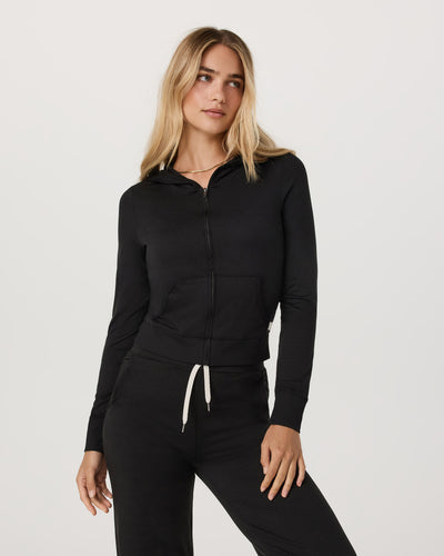 Woman wearing a Vuori - Halo Mini Full Zip Hoodie and pants on a white background