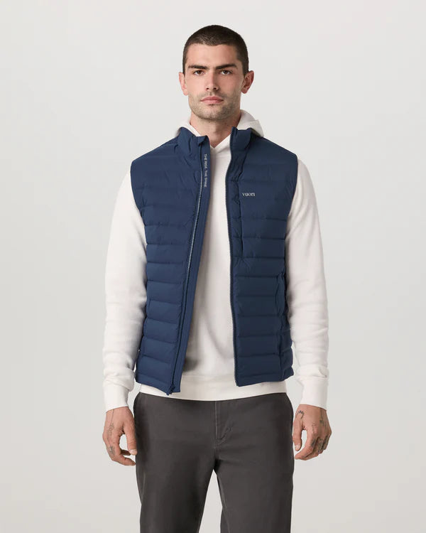 Man wearing a Vuori - Steadfast Insulated Vest over a white Vuori sweater on a light gray background