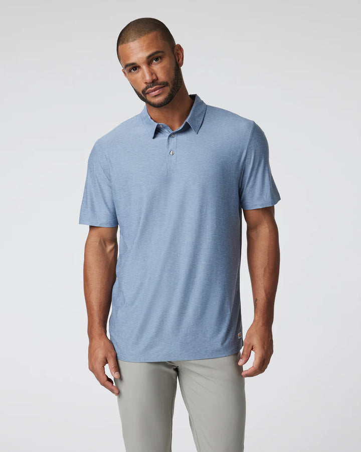 A man wearing a Vuori - Strato Tech Polo in Chambray Heather with short sleeves and a collar.