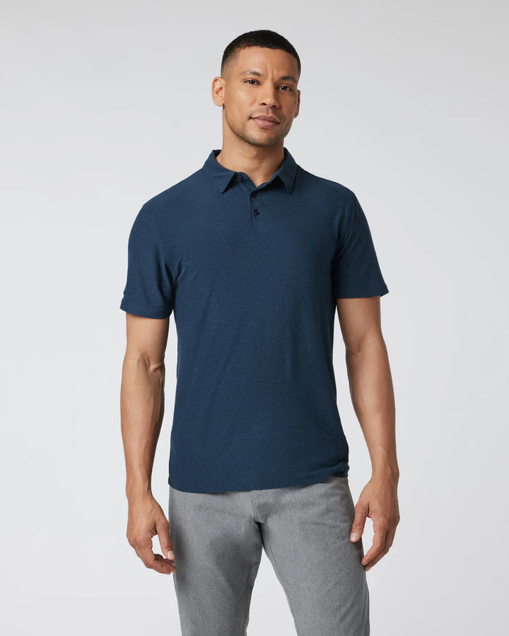 A man wearing a Vuori - Strato Tech Polo in Navy Heather with short sleeves and a collar.