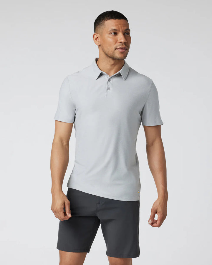 A man wearing a Vuori - Strato Tech Polo in Platinum Heather with short sleeves and a collar.
