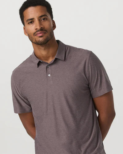 Man wearing a Vuori - Strato Tech Polo in Timber Heather against a plain background
