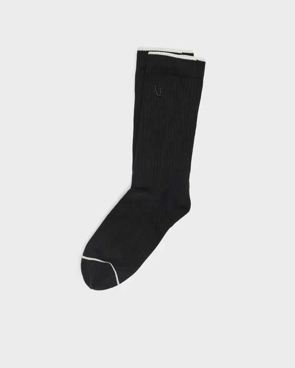 Black Vuori V1 Crew Sock with white trim on a light gray background